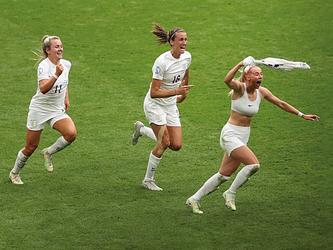 Three members of the English womans football team celebrating on the pitch after winning the 2022 euros